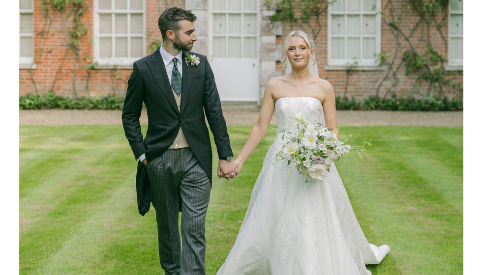 Bride and groom pose before the Georgian house venue at their Hampshire garden wedding.