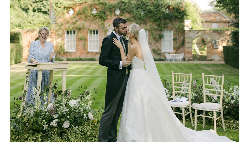 Bride, groom, and celebrant at outdoor wedding ceremony by Georgian house in Hampshire