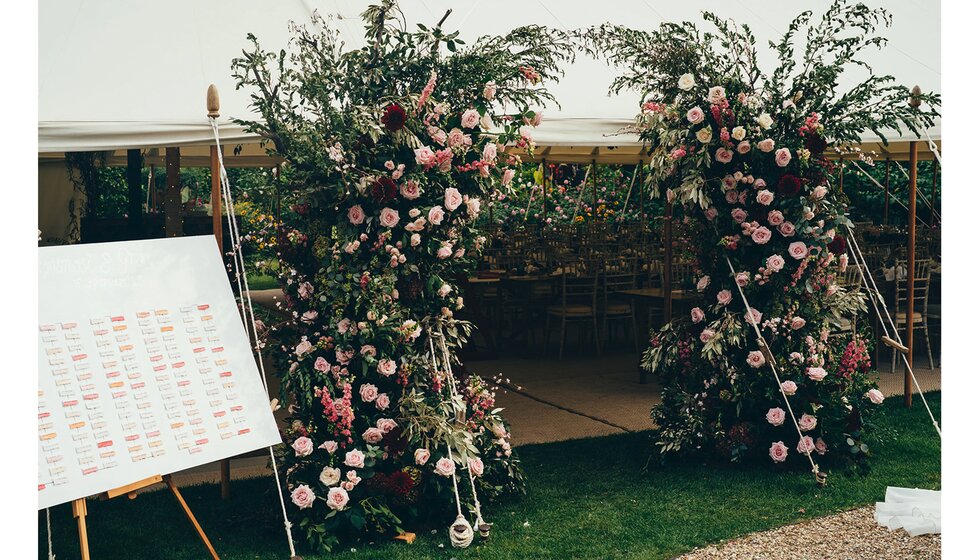 A floral arch with roses outside the wedding marquee entrance