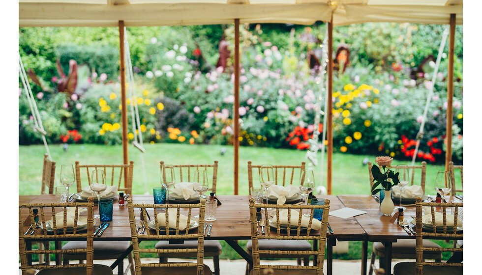 Simple neutral marquee table setting for a wedding in a colourful Sussex garden