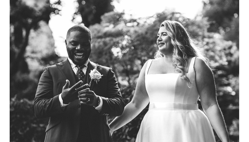 Happy groom and bride pose in the garden after getting married.