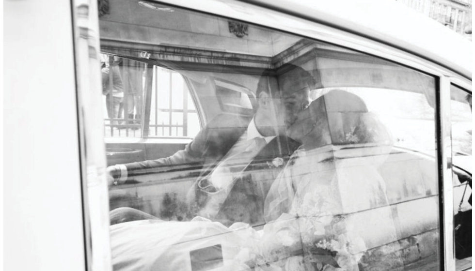 The bride and groom share a kiss in their vintage Rolls Royce.