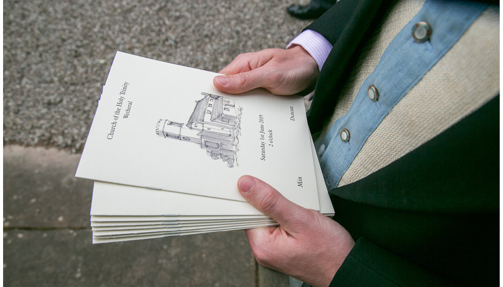 An usher hands out the order of services outside the church.