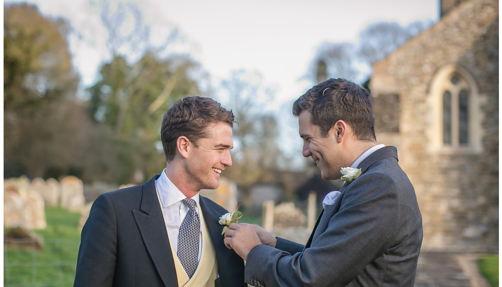 The groom's best man adjusting his button hole outside the Church.