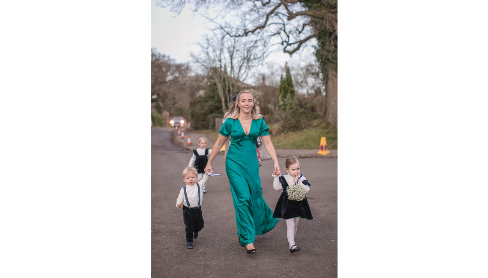 A page boy and bridesmaid being walked into the church.