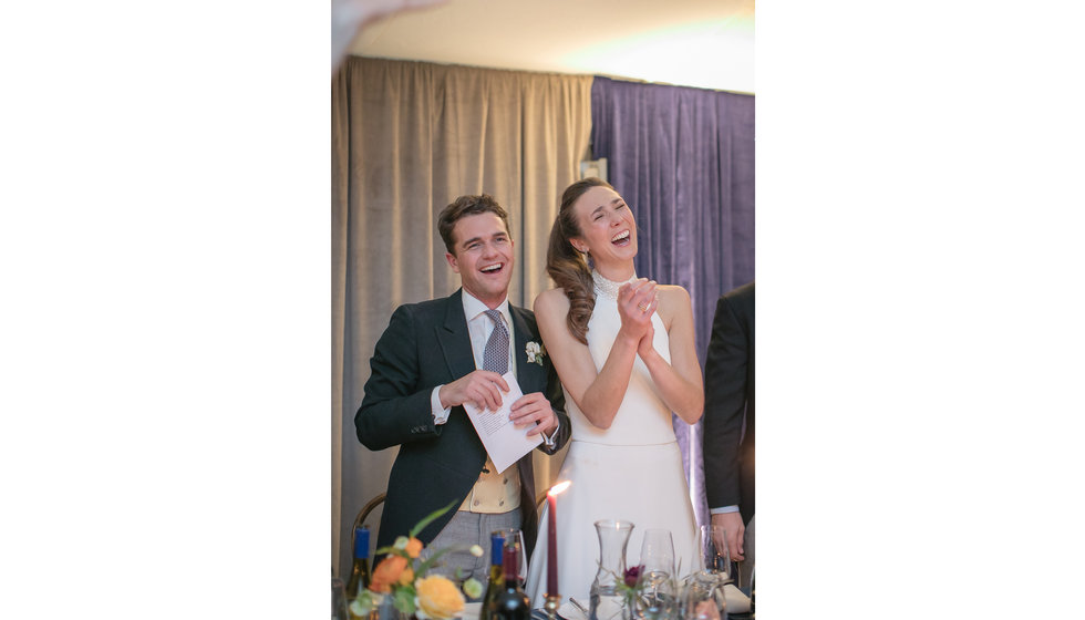 The bride and groom laughing during the speeches.