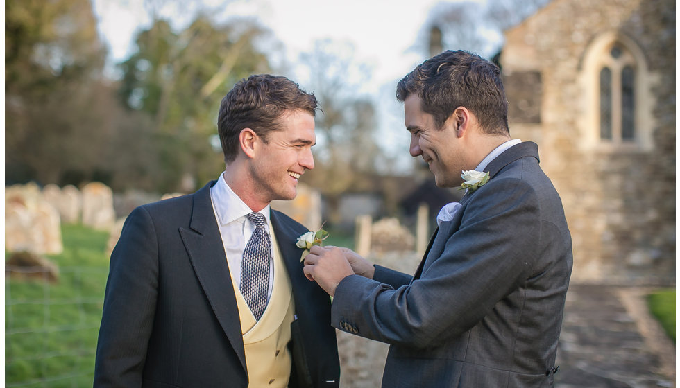 The groom being helped with his button hole.