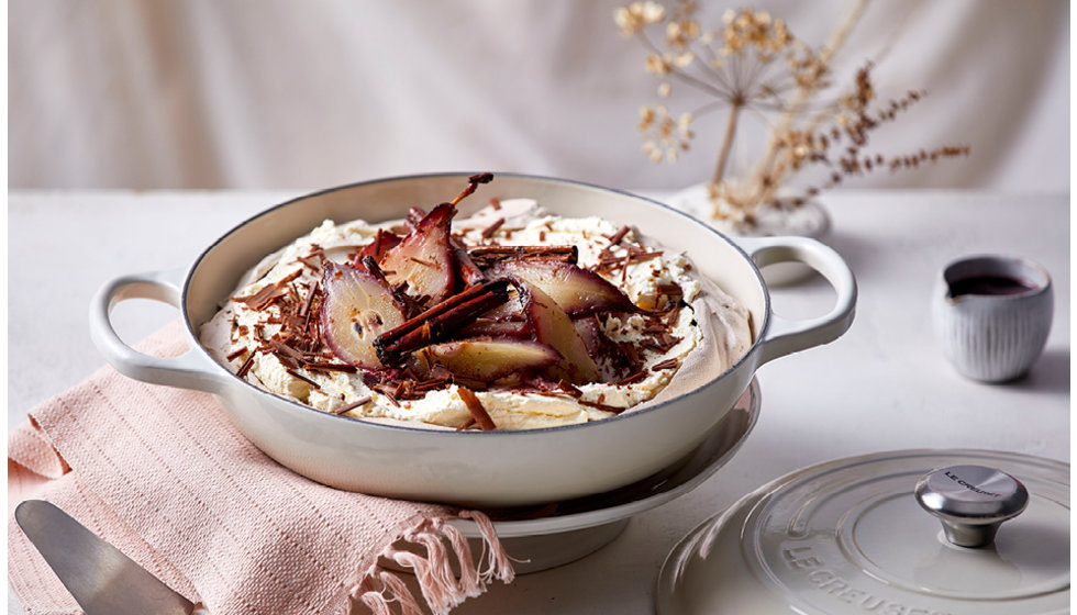 A meringue coloured shallow casserole filled with cooked pears inside.