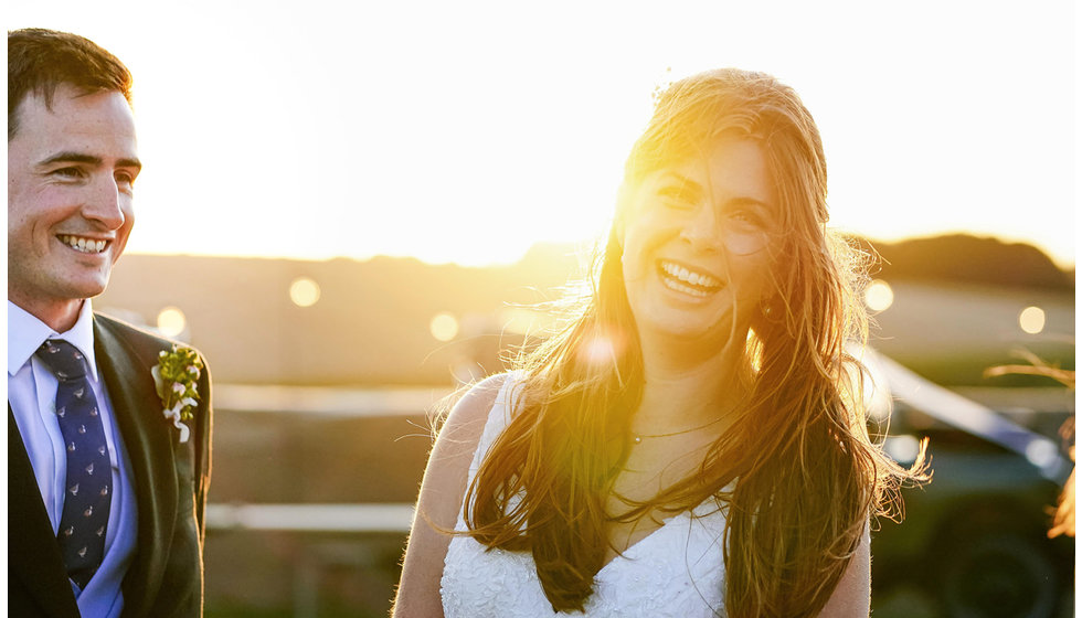 The bride and groom laughing with golden light behind them.