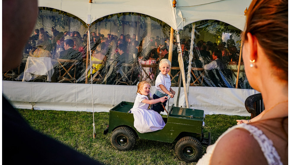 Two little children driving a mini landrover.