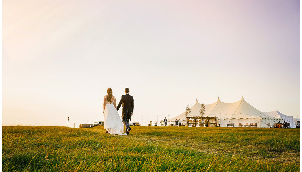 Josh and Victoria walking towards their traditional marquee.