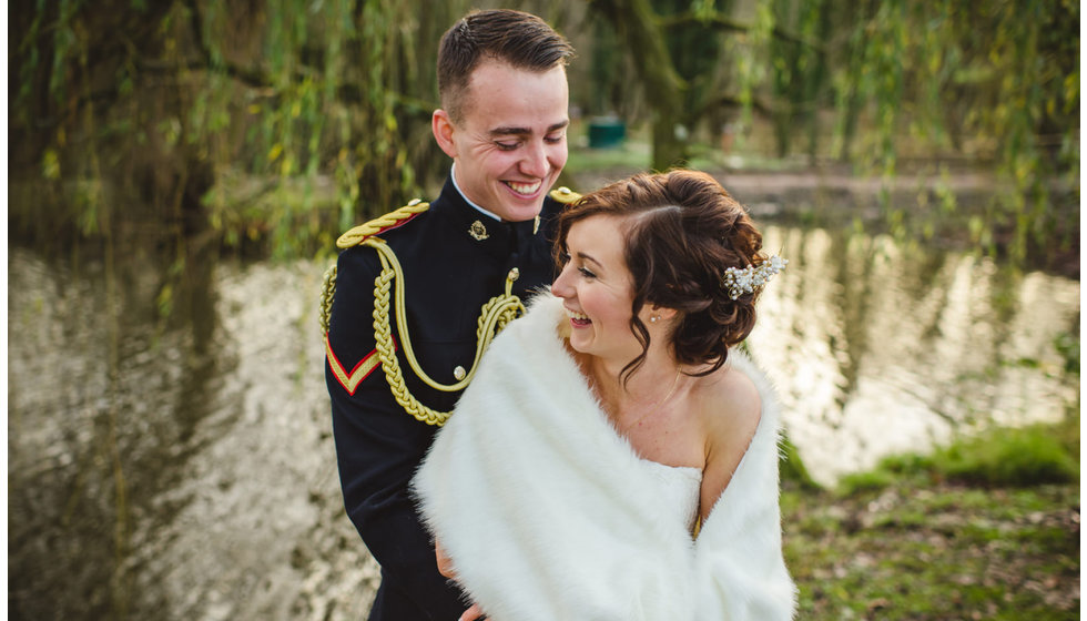 A couple in winter light in front of a lake.