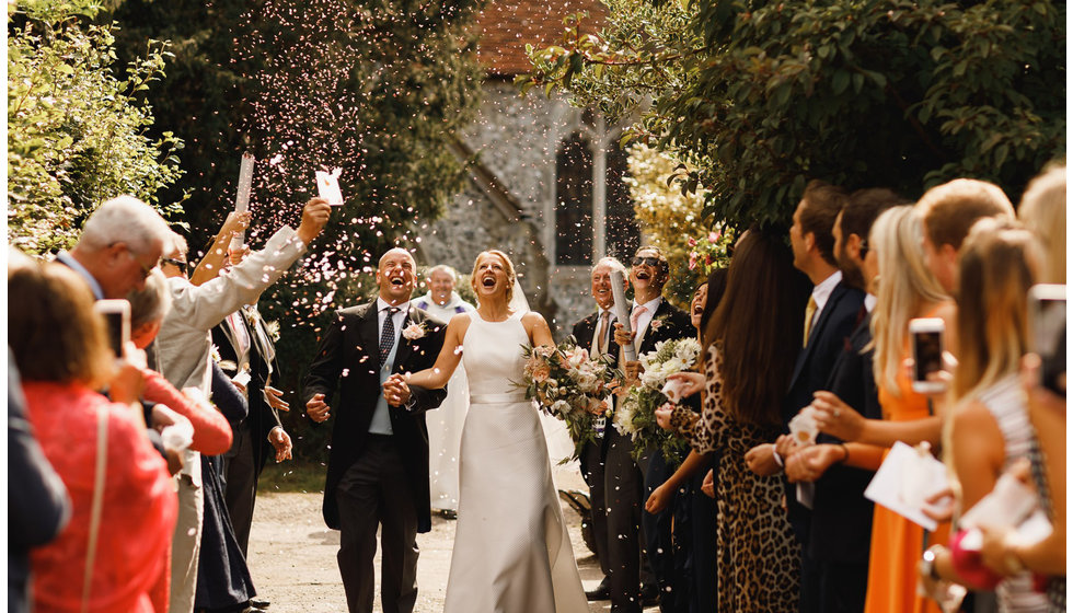 The bride and groom walking down their guests at the wedding.