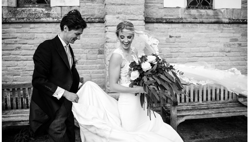 Sam holds Rebecca's dress as they come out of the Church.