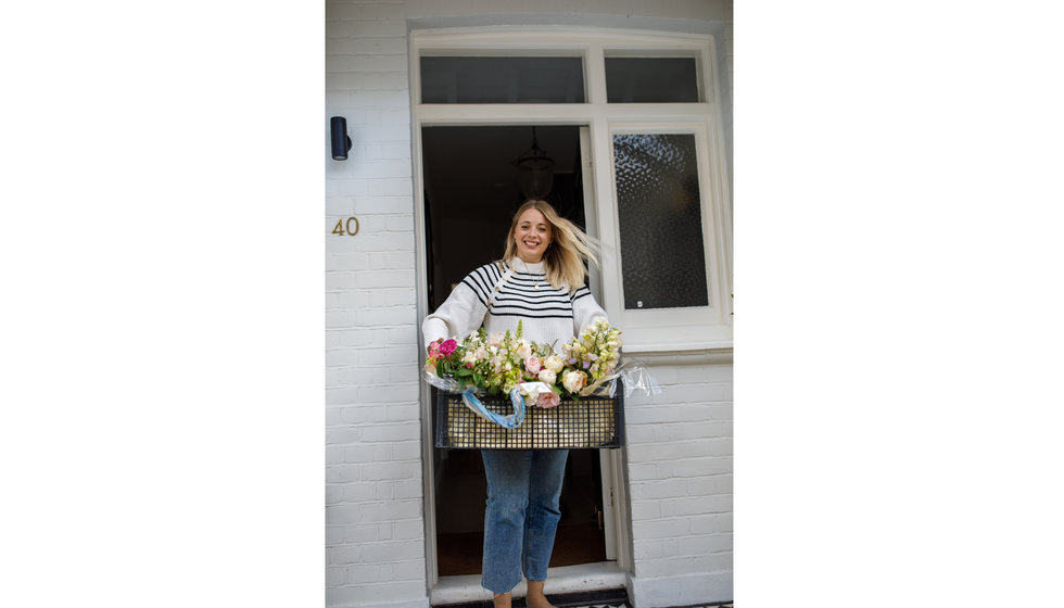 Georgie outside her front door with the flowers in a crate.