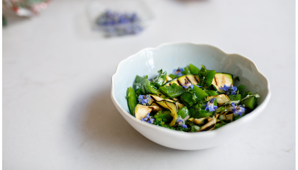 A delicious fresh courgette salad with edible flowers served in a beautiful hand glazed scalloped bowl by JARS.