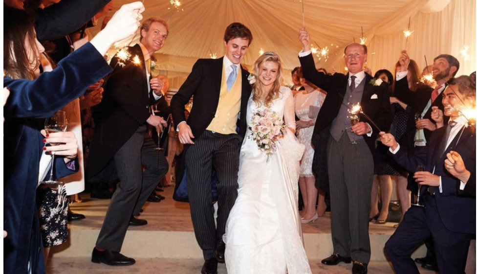 The bride and groom leave the marquee with their wedding guests all holding sparkers as they leave.