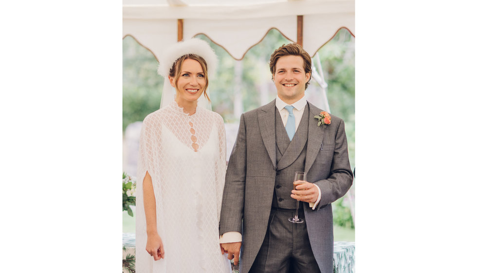 The bride and groom smiling during the speeches in their intimate marquee wedding.