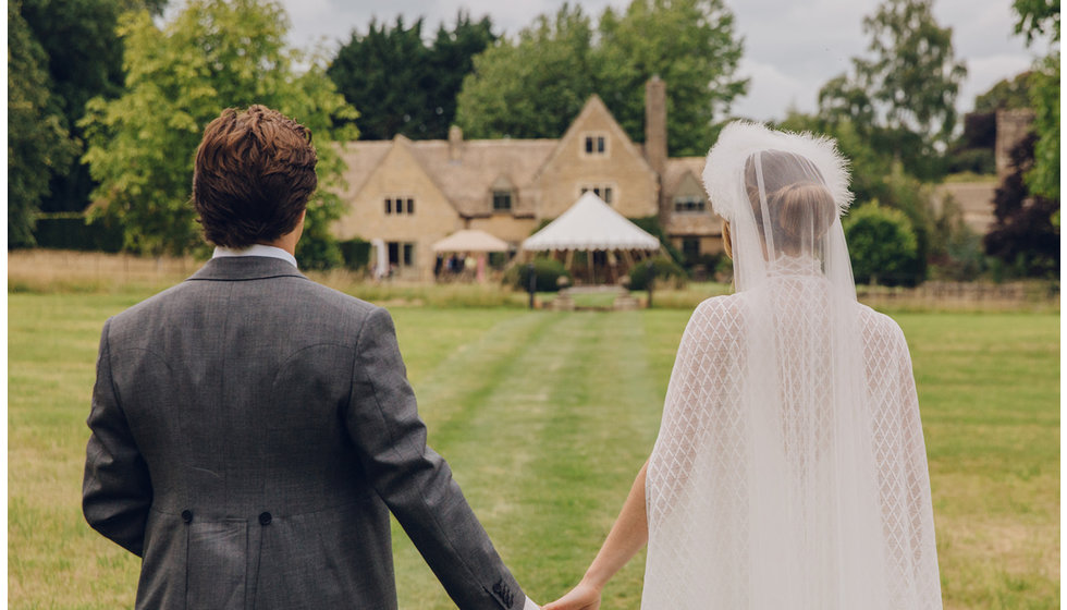 The bride and groom holding hands before their marquee in the grounds of Jack's parent's house.