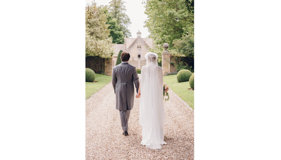 The bride and groom pose for their formal photos in the foreground of the groom's family home.