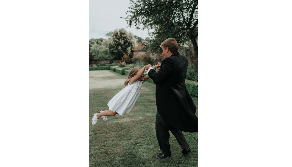 A bride swinging round one the flower girls.