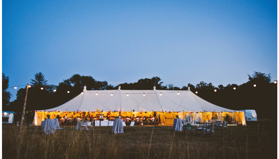 A marquee at dusk lit up with festoon lights.