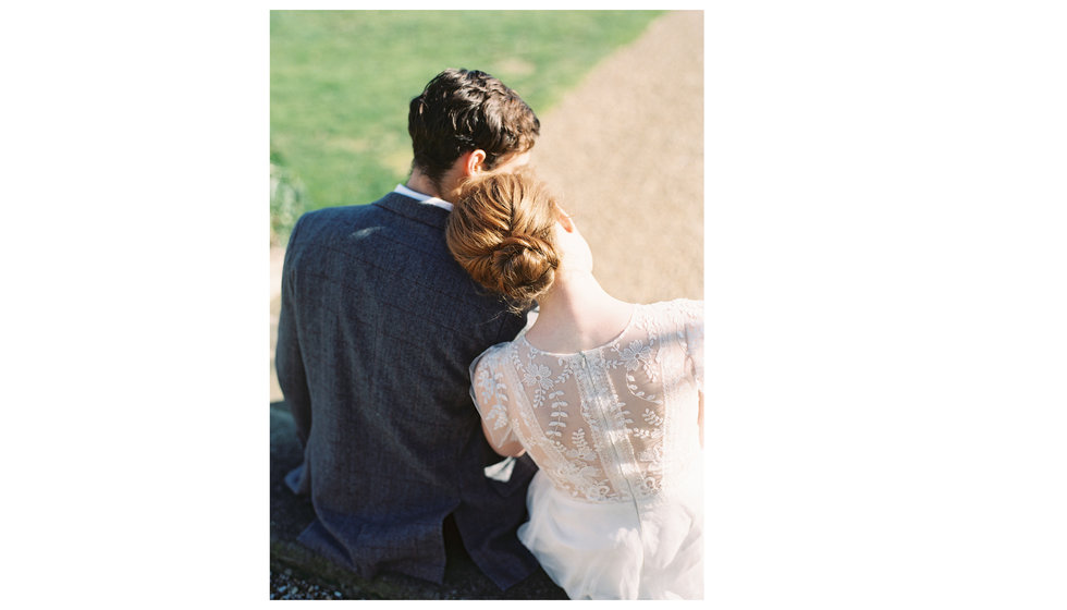 A model bride leaning on her husbands shoulder from behind.