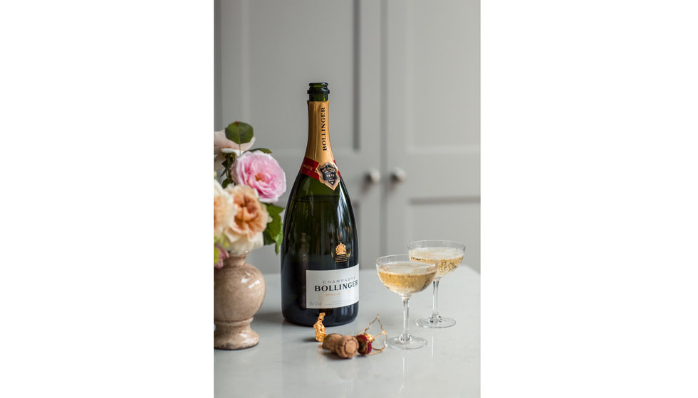 A magnum of Bollinger next to two couples of poured champagne.