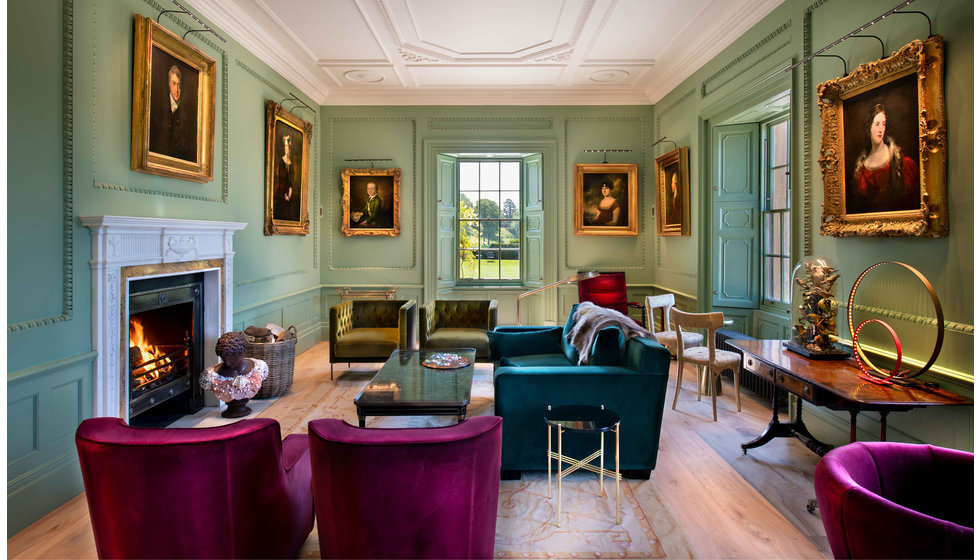 A sitting room within the Newt Hotel in Somerset. The room is modern yet traditional filled with gold frames and velvet furniture.