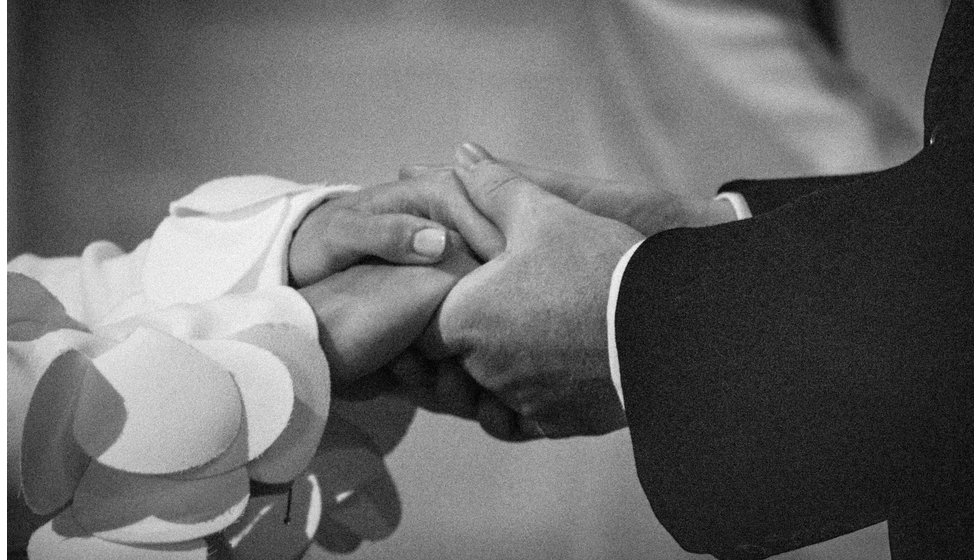 The bride and groom holding hands whilst doing their vowes.