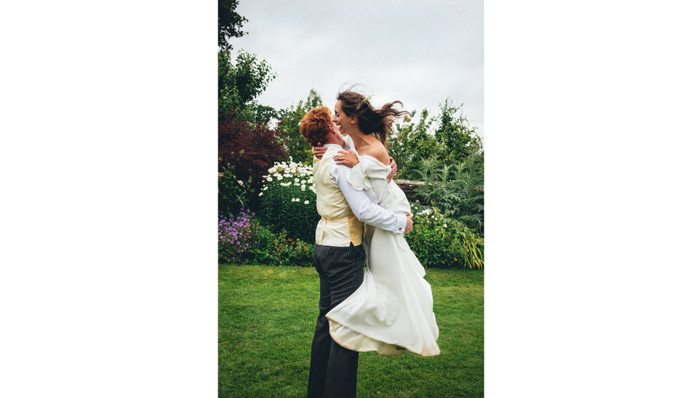 The groom lifting the bride up in the garden.