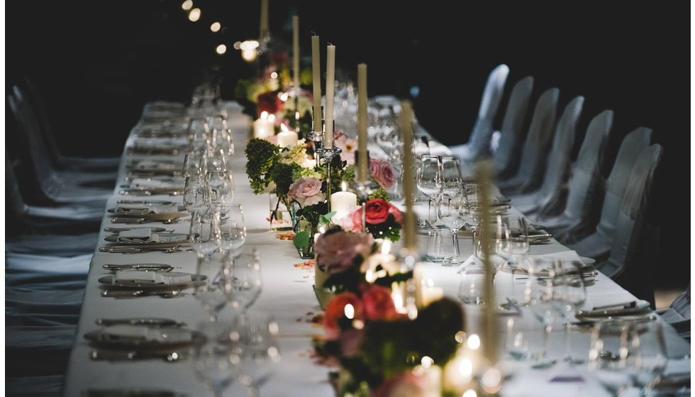 The table laid for 27 people, with roses and tea lights down the centre at the Cannaught Hotel.