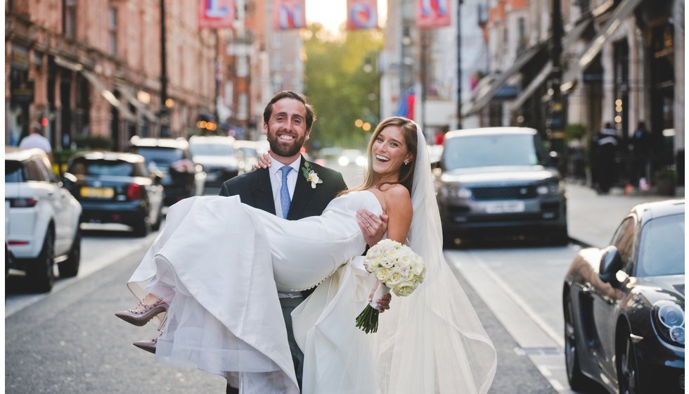 The groom lifts the bride up in the middle of the street.