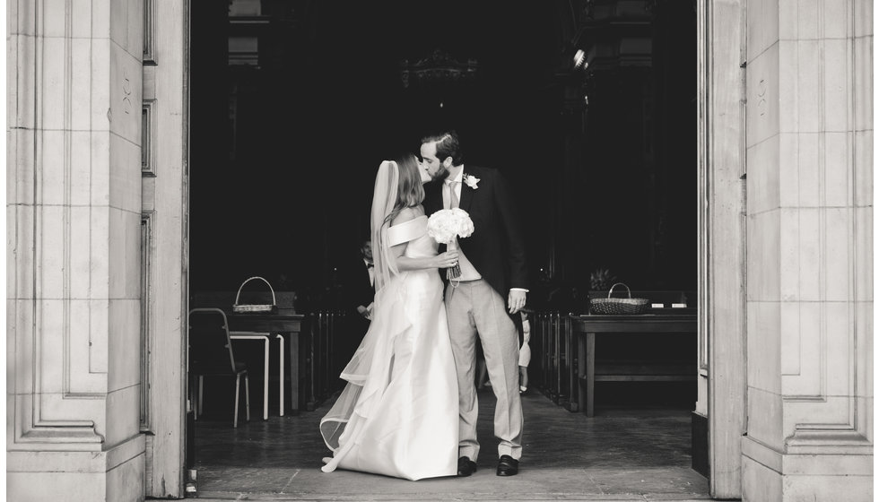 The bride and groom share a kiss on the steps of the Brompton Oratory where the couple married.