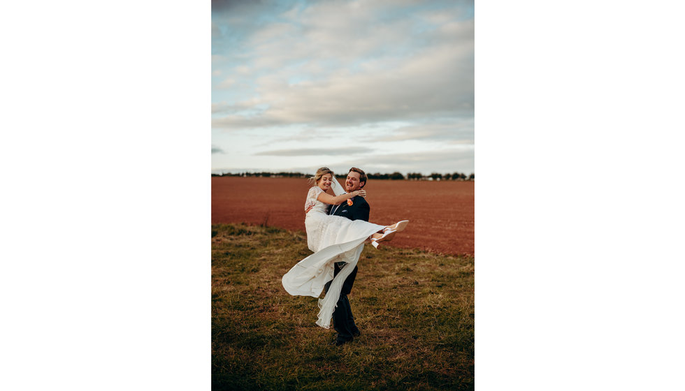 The groom lifting up the bride laughing in the Herefordshire Countryside.