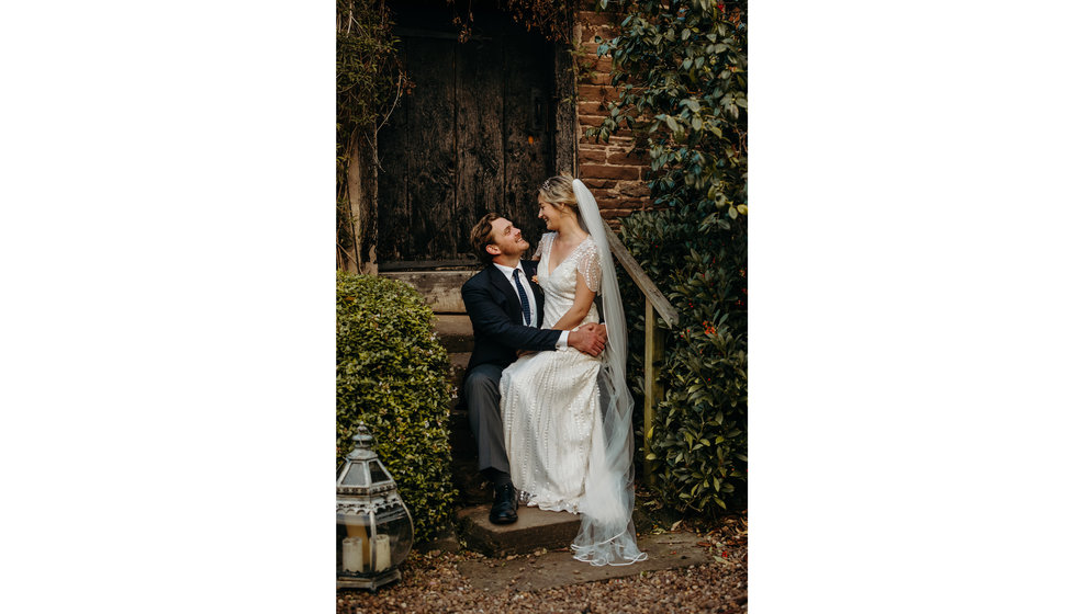 The bride sitting on the grooms lap on their wedding day.