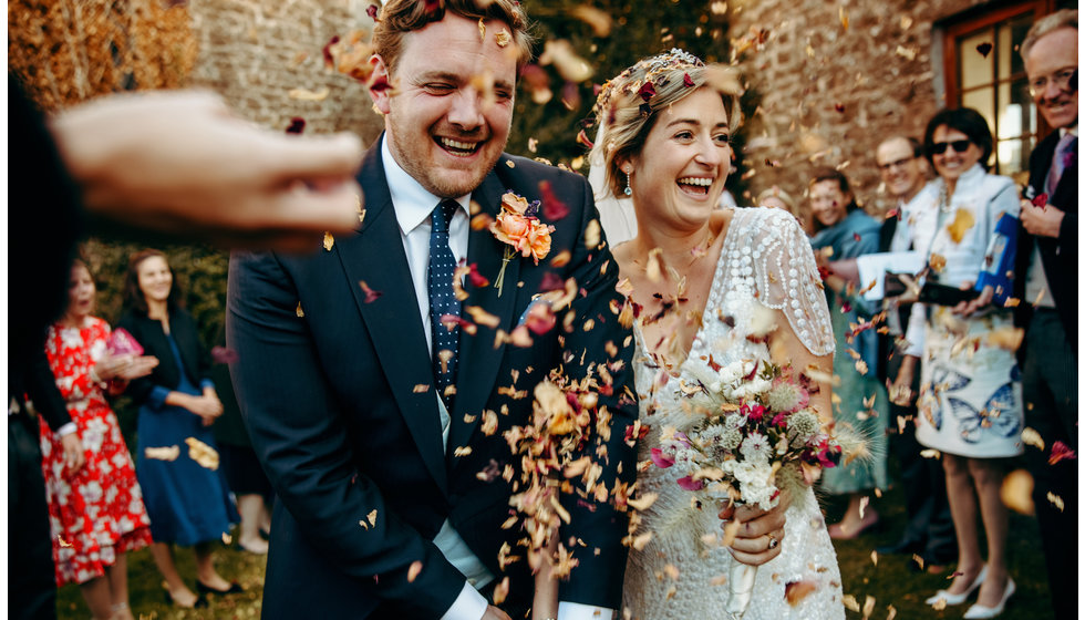 The bride and groom walking through hand dried confetti.