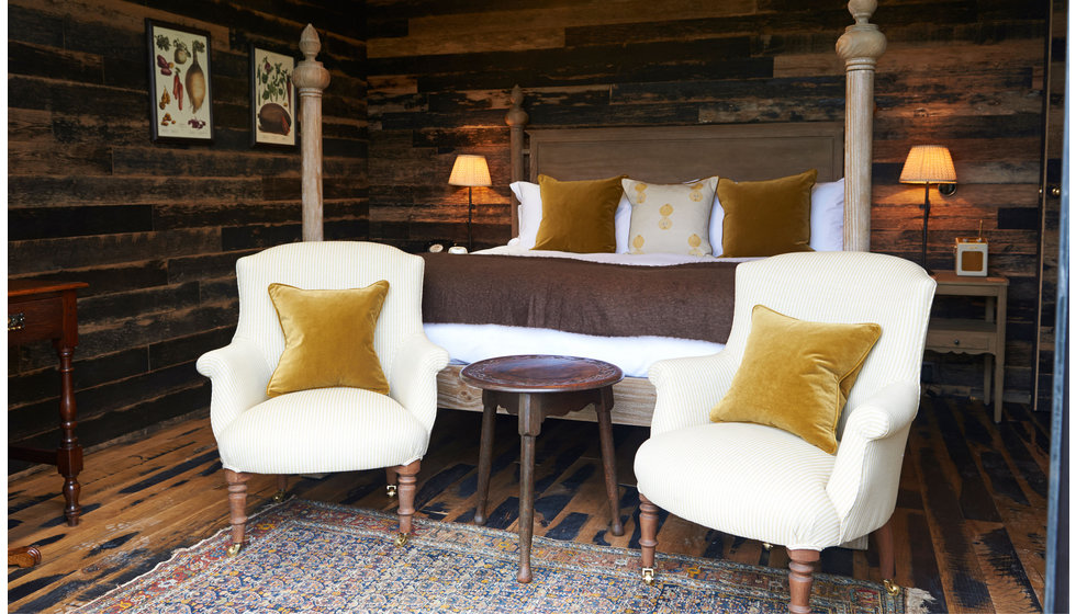 A cozy bedroom in The Pig Hotel bedroom with armchairs at the end of the bed.