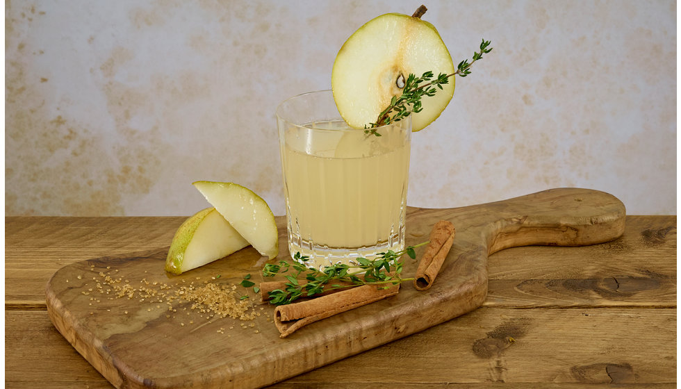 A spiced Pear cocktail served on a wooden board.