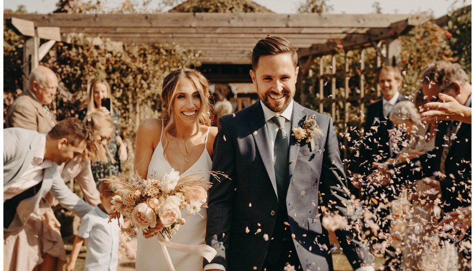 The bride and groom walking through their guests throwing confetti.