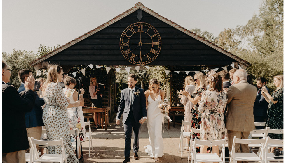 The bride Louise and groom Matthew walking down from their outdoor ceremony with their intimate amount of guests.