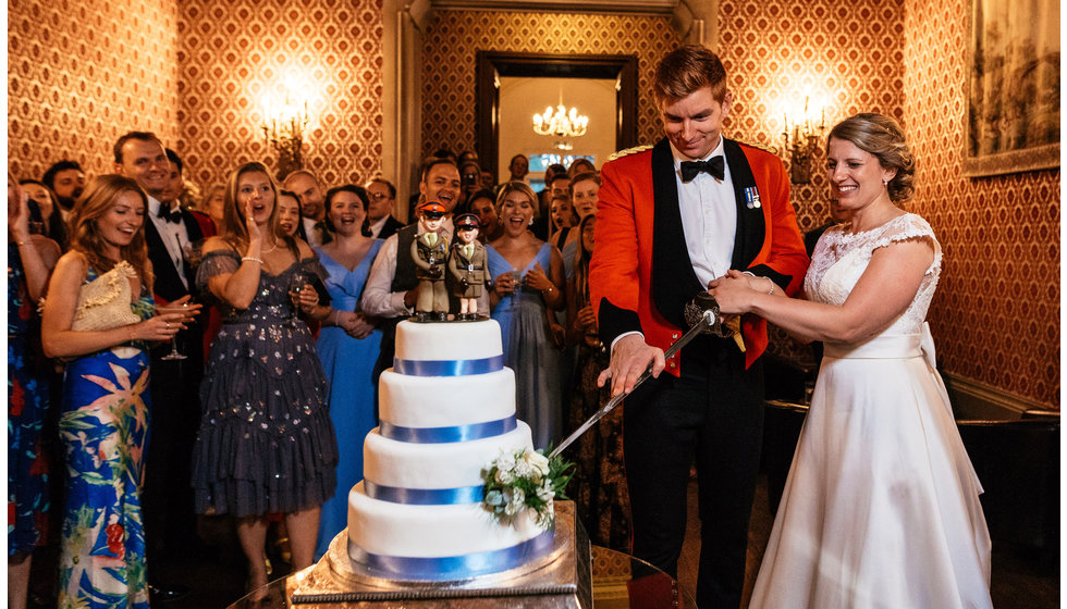 The bride and groom cutting their wedding cake with a personal military twist. 