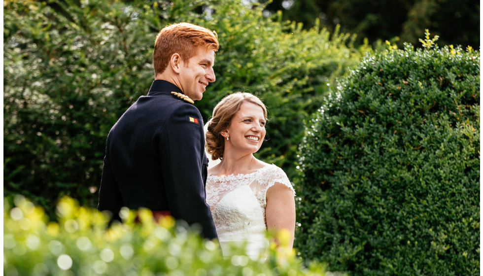 The bride and groom have their professional photos taken outside their wedding venue. 