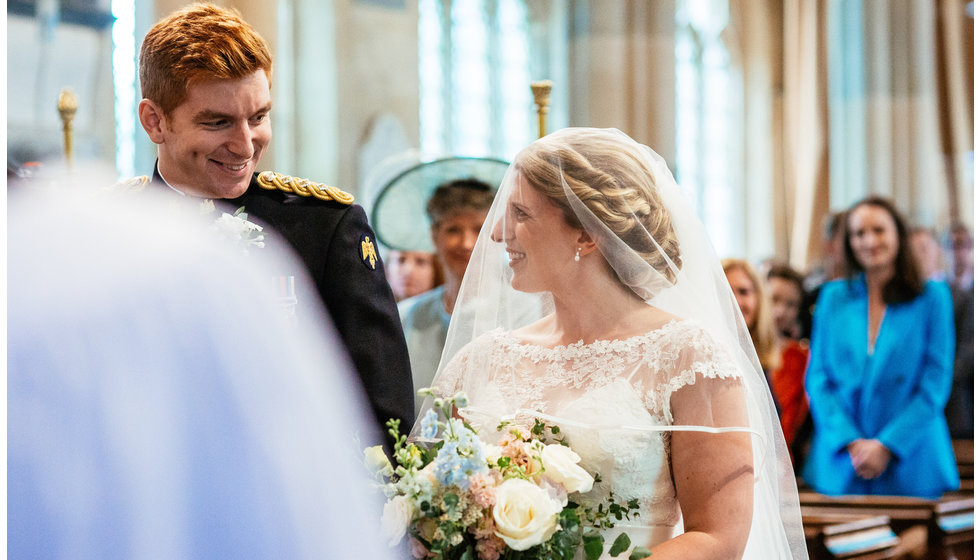 The bride and groom smiling at each other in the Church.