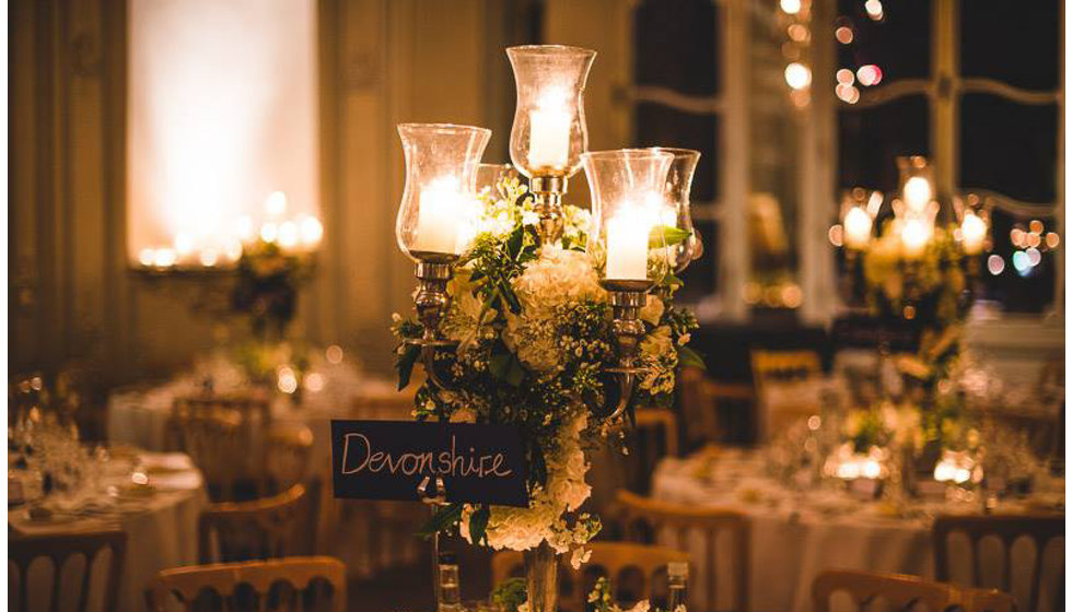 The details of the tables for Will and Lexie's wedding reception in the Savile Club. Tables adorned with greenery and candles.