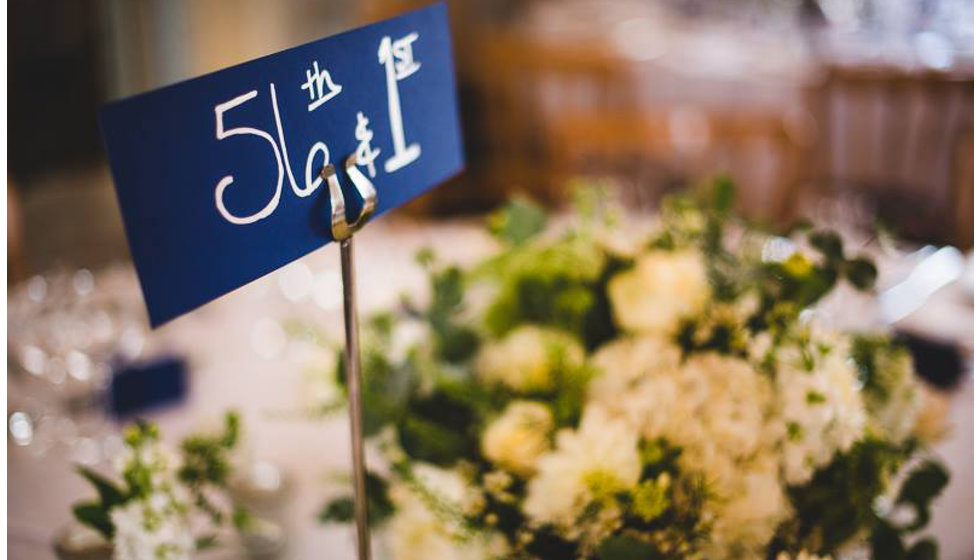 Details of the flowers and the table names at the couples wedding breakfast in the The Savile Club in London.