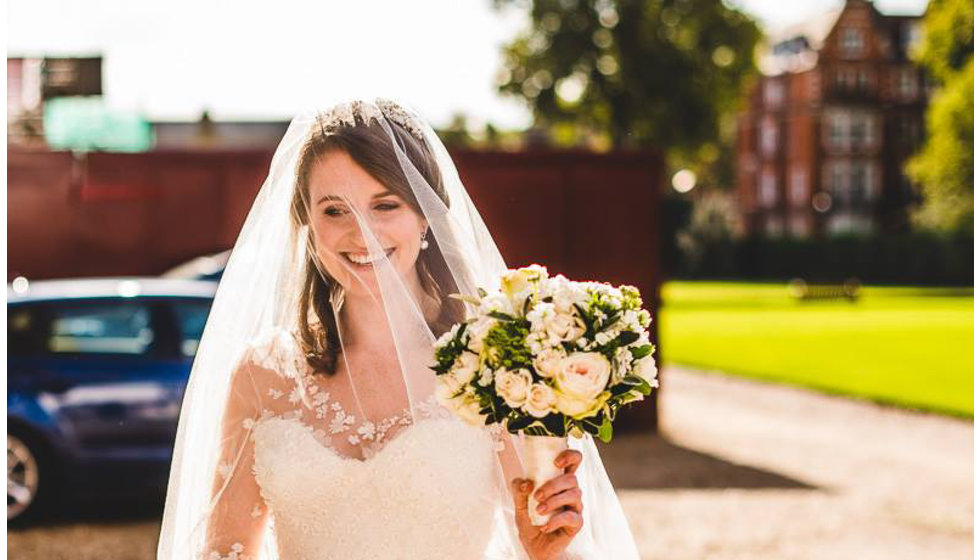 The bride arriving to the Royal Hospitsal in Chelsea wearing a Sassi Holford wedding dress, veil and holding her bouquet of white roses.