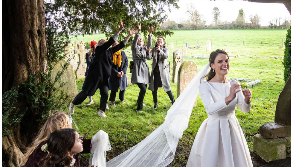 The bride throwing a bouquet to her friends outside the Church.