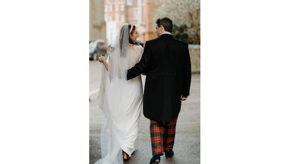 Sarah and Fergus walking to their wedding reception in Sarah's mother's garden.