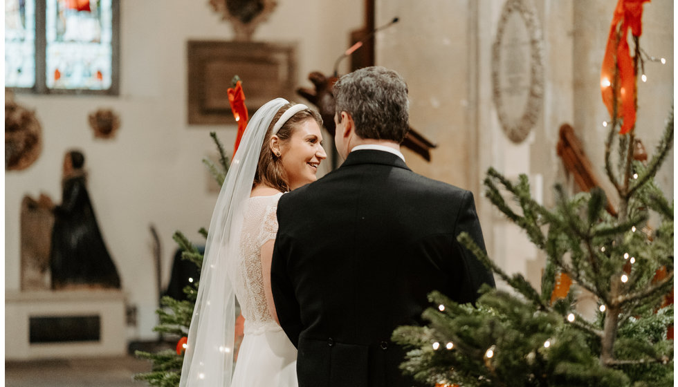 Sarah and Fergus at the alter next to two Christmas trees.